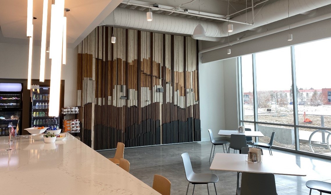 The floor-to-ceiling Skyline Café Focal Wall piece was created especially for Jacobsen from reclaimed wood sourced from the company’s own materials yard. This multi-dimensional piece is layered to represent the depth of Jacobsen’s important work and rises tall as a testament to the company’s bright future. The city horizon line found within the piece symbolizes the elevating skyward reach of the gleaming cities and the thriving communities Jacobsen builds.